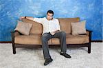 Lazy young Caucasian man sits in middle of couch