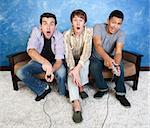 Three excited friends with controllers play video games