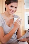 Young woman drinking tea while reading newspaper