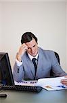 Young businessman getting a headache from looking at paperwork