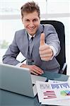 Happy businessman at his desk giving thumb up