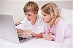 Cute children using a laptop in a bedroom