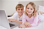 Cute children using a notebook in a bedroom