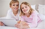 Children using a tablet computer in a bedroom