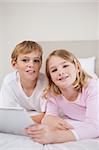 Portrait of children using a tablet computer in a bedroom