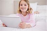 Girl using a tablet computer in a bedroom