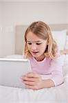 Portrait of a little girl using a tablet computer in a bedroom