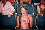 Screaming woman with popcorn bag in theater