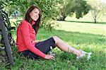 Young woman sitting on the grass holds bottle of water near bicycle