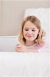 Portrait of a smiling little girl using a tablet computer in a bedroom