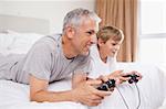 Smiling father and his son playing video games in a bedroom