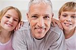 Close up of siblings and their father posing in a bedroom