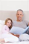 Portrait of a father reading a story to his daughter in a bedroom