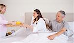 Girl serving breakfast to her parents in their bedroom