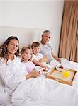 Portrait of a family having breakfast in a bedroom while looking at the camera