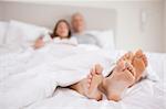 Couple lying in a bed with the camera focus on their feet