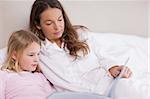 Little girl reading a book with her mother in a bedroom