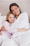 Portrait of a mother and her daughter hugging in a bedroom