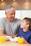 Portrait of a young boy and his father having breakfast in a kitchen