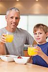 Portrait of a cute boy and his father having breakfast in a kitchen