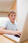 Portrait of a blond boy using a notebook in a kitchen