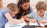 Mother helping her children to do their homework in a living room