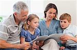 Family reading a book together in a living room