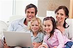 Delighted family using a laptop in a living room