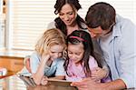 Happy family using a tablet computer together in a kitchen