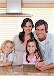 Portrait of a smiling family using a tablet computer together in a kitchen