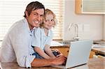 Boy and his father using a notebook together in a kitchen