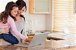 Girl and her mother using a laptop in a kitchen