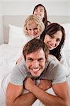 Portrait of a happy family lying on each other in a bedroom