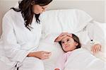 Mother checking on her daughter's temperature in a bedroom