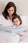 Portrait of a mother reading a story to her daughter in a bedroom