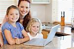 Mother together with children on the laptop in the kitchen