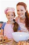 Smiling mother and daughter with ingredients for cookies