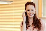 Smiling woman with cellphone in the kitchen