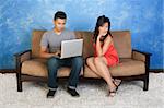 Unhappy Hispanic girlfriend with boyfriend using laptop