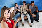 Annoyed young Caucasian woman with three men playing video games