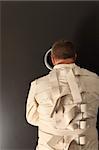 Photo of a insane man in his forties wearing a straitjacket looking out the hole of an asylum door.