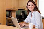 Smiling woman in the kitchen with her notebook