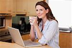 Woman drinking coffee while on her laptop