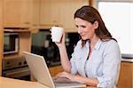 Woman drinking tea while on her laptop