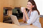 Smiling woman with cup and notebook in the kitchen