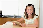 Smiling girl with tablet at the kitchen table
