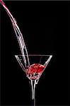 Pouring a red spirit in a Martini glass on black