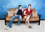 Smiling young Caucasian man with frustrated woman sit on sofa