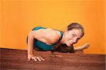 Smiling Caucasian woman performs yoga on a wooden mat