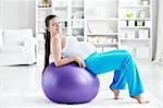 A pregnant young woman is doing on fitball